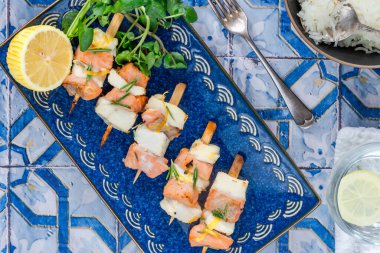 Mini somon ve halibut şişleri bal, biberiye ve limonla marine edilmiş.