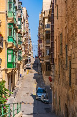 VALLETTA, MALTA - 30 Ağustos 2024: Geleneksel Malta binaları ve renkli balkonları ile Valletta 'da Dar Sokak. Valletta Malta 'nın başkentidir ve çok popüler bir turist merkezidir.