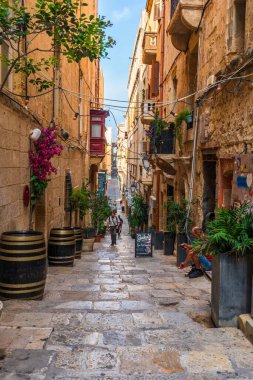 VALLETTA, MALTA - 30 Ağustos 2024: Geleneksel Malta binaları ve renkli balkonları ile Valletta 'da Dar Sokak. Valletta Malta 'nın başkentidir ve çok popüler bir turist merkezidir.