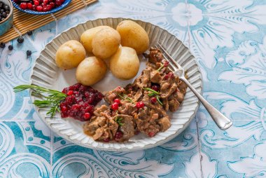 Geleneksel Norveç ren geyiği güveci, yaban mersini ve haşlanmış patates.