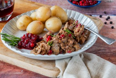 Geleneksel Norveç ren geyiği güveci, yaban mersini ve haşlanmış patates.