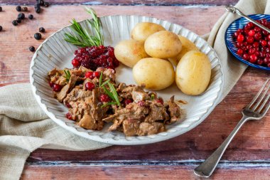 Geleneksel Norveç ren geyiği güveci, yaban mersini ve haşlanmış patates.