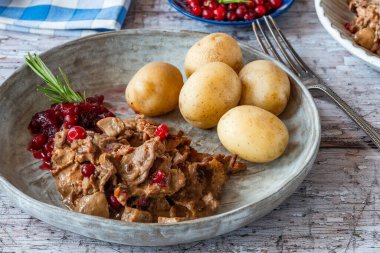 Geleneksel Norveç ren geyiği güveci, yaban mersini ve haşlanmış patates.