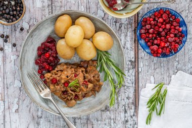 Geleneksel Norveç ren geyiği güveci, yaban mersini ve haşlanmış patates.