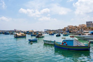 MARSAXLOKK, MALTA - SEPTEMBER 03, 2024: Geleneksel renkli balıkçı tekneleri, Malta 'nın küçük bir balıkçı kasabası olan Marsaxlokk limanına demirlemişti..