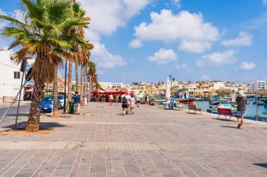 MARSAXLOKK, MALTA - SEPTEMBER 03, 2024: Marsaxlokk, Malta kıyılarında küçük, pitoresk bir balıkçı köyüdür. Turistler arasında görüşleri, balıkçılık ve tarihi açısından popülerdir..