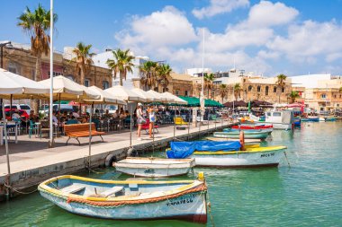 MARSAXLOKK, MALTA - SEPTEMBER 03, 2024: Geleneksel renkli balıkçı tekneleri, Malta 'nın küçük bir balıkçı kasabası olan Marsaxlokk limanına demirlemişti..
