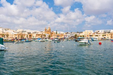 MARSAXLOKK, MALTA - SEPTEMBER 03, 2024: Geleneksel renkli balıkçı tekneleri, Malta 'nın küçük bir balıkçı kasabası olan Marsaxlokk limanına demirlemişti..