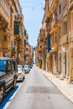 VALLETTA, MALTA - 30 Ağustos 2024: Geleneksel Malta binaları ve renkli balkonları ile Valletta 'da Dar Sokak. Valletta Malta 'nın başkentidir ve çok popüler bir turist merkezidir.