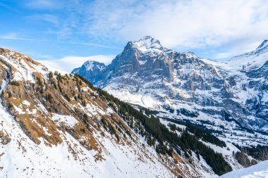 İsviçre 'nin Grindelwald kayak merkezindeki İsviçre Alpleri' nin ilk dağından görülen karla kaplı tepeleriyle kış manzarası