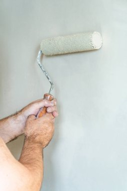 Dekoratörün elleri bir duvar boyuyor - ev yenileme konsepti - seçici odak