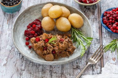 Geleneksel Norveç ren geyiği güveci, yaban mersini ve haşlanmış patates.