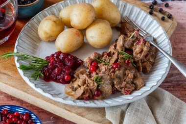 Geleneksel Norveç ren geyiği güveci, yaban mersini ve haşlanmış patates.