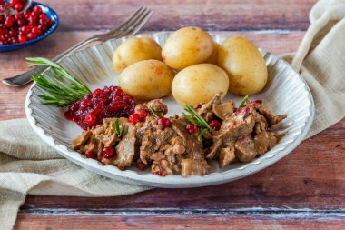 Geleneksel Norveç ren geyiği güveci, yaban mersini ve haşlanmış patates.