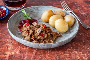 Geleneksel Norveç ren geyiği güveci, yaban mersini ve haşlanmış patates.