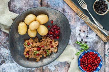 Geleneksel Norveç ren geyiği güveci, yaban mersini ve haşlanmış patates.