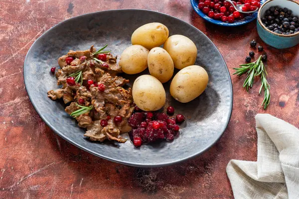 Geleneksel Norveç ren geyiği güveci, yaban mersini ve haşlanmış patates.