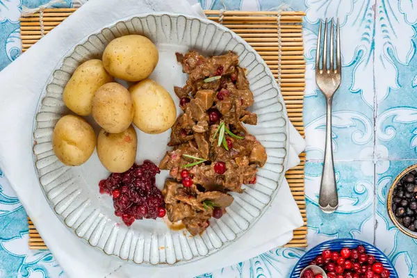 Geleneksel Norveç ren geyiği güveci, yaban mersini ve haşlanmış patates.