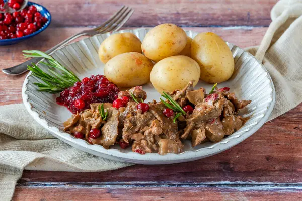 Geleneksel Norveç ren geyiği güveci, yaban mersini ve haşlanmış patates.