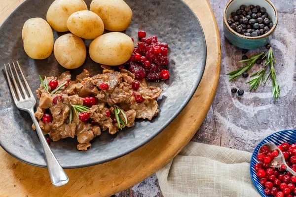 Geleneksel Norveç ren geyiği güveci, yaban mersini ve haşlanmış patates.