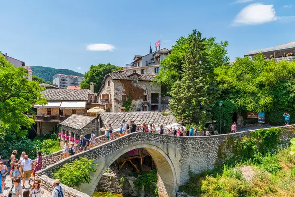 MOSTAR, BOSNIA-HERZEGOVINA - Haziran 07, 2025: Bosna-Hersek 'in güneyindeki Mostar' ın Eski Kenti 'ndeki taş köprüde yürüyen insanlar, Neretva Nehri' nin kıyısında yer alıyor..