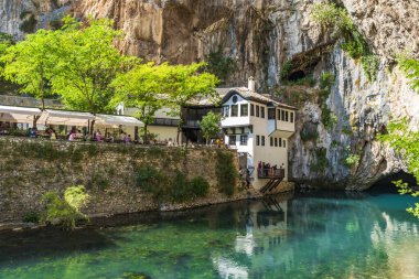 BLAGAJ TEKIJA, BOSNIA-HERZEGOVINA - HAZİRAN 08, 2025: Turistler, Bir uçurumun dibinde, Buna nehrinin kaynağının yanındaki 600 yıllık tarihi Derviş Evi 'ni ziyaret ediyorlar.