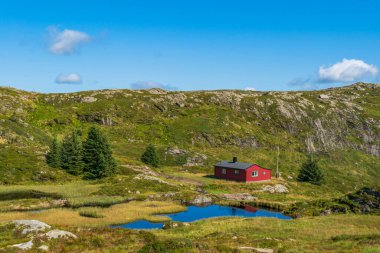 Bergen, Norveç yakınlarındaki Ulriken Dağı 'nda küçük bir gölü ve kırmızı ahşap kulübesi olan güzel bir manzara.