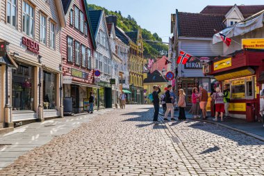 BERGEN, NORway - 15 AĞUSTOS 2025: Geleneksel renkli İskandinav binaları Norveç 'in Bergen kentindeki kaldırımlı bir cadde üzerindedir. Bergen Norveç 'in güneybatı kıyısında dağlar ve fiyortlarla çevrili bir şehirdir.