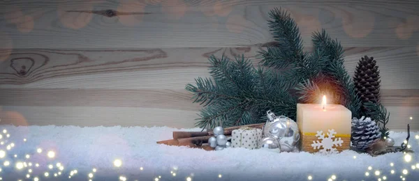 Advent candle and christmas decoration isolated on wood background. Christmas background with snow,candle and bauble.