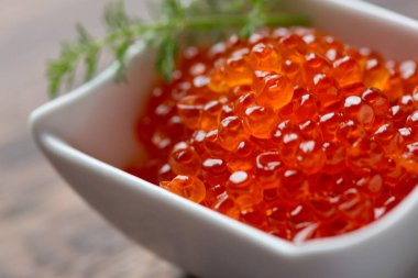 Red Caviar in bowl over wood background. Close-up salmon caviar