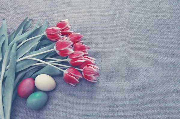 Tulips and easter Eggs on brown cloth Background.Spring greeting card.