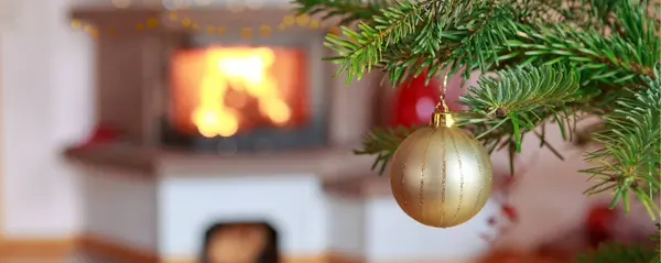 Altın Küreli Yanan Şömine Arkaplanlı Noel Ağacı Dalı — Stok fotoğraf