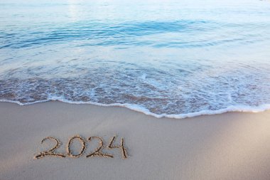 Happy New Year 2024 text on the sea beach. Handwritten inscription 2024 on beautiful white sand beach clipart