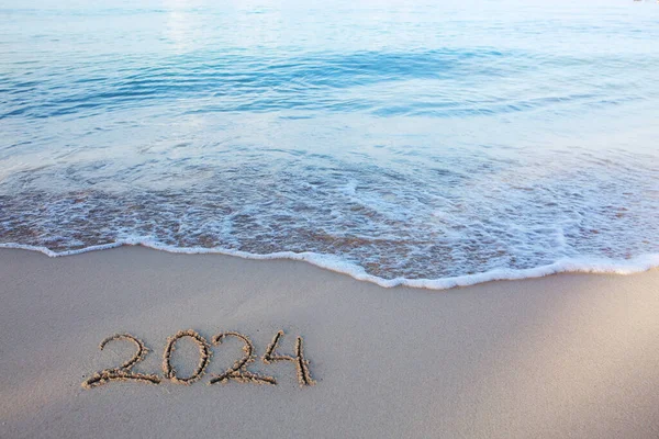 Deniz sahilinde 2024 yılınız kutlu olsun. Güzel beyaz kumsalda el yazması 2024.