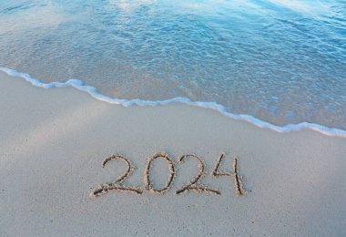 Deniz sahilinde 2024 yılınız kutlu olsun. Güzel beyaz kumsalda el yazması 2024.