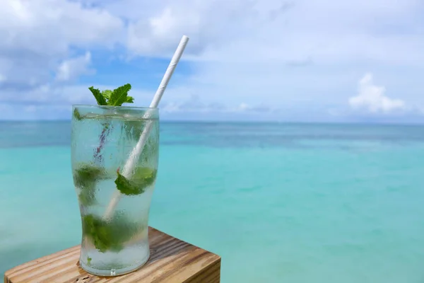 Beach cocktail with straw on Caribbean beach.