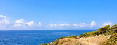 Kaya kıyısındaki mavi gökyüzü ve deniz plajı.
