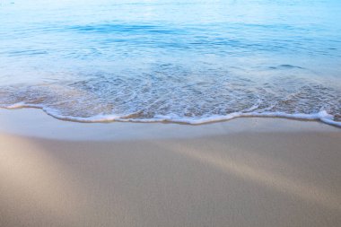 Karayip kumlu sahilinde yumuşak mavi okyanus dalgası.