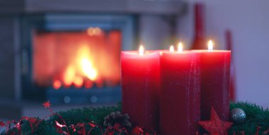 Şömineli sıcak bir iç mekanda yanan dört kırmızı Advent mumu..