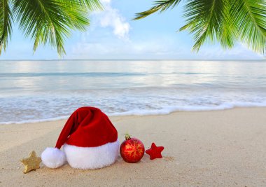 Beyaz Karayip kumu üzerinde Noel Baba şapkası. Yeni yıl ve Noel arkaplanı .
