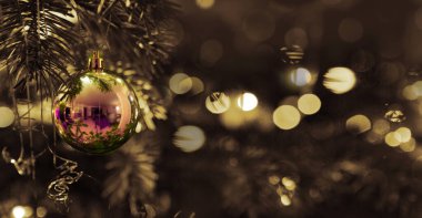 Köknar ağacındaki kırmızı Noel yıldızına yaklaş. Arka planda Bokeh çelenkleri.