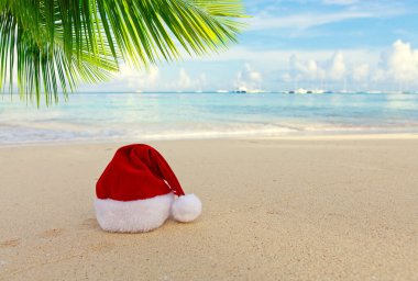 Beyaz Karayip kumu üzerinde Noel Baba şapkası. Yeni yıl ve Noel arkaplanı .