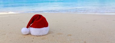Mutlu Noeller Noel Baba şapkası beyaz Karayip kumlarında.