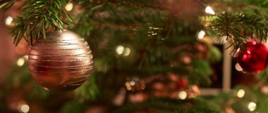 Köknar ağacındaki altın noel balosuna yaklaş. Arka planda Bokeh çelenkleri.