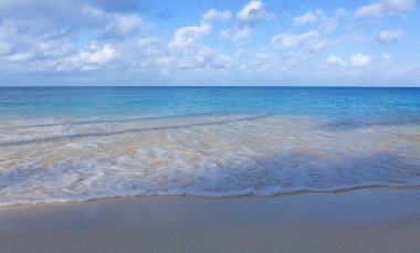 Karayip kumlu sahilinde yumuşak bir mavi okyanus dalgası. Seyahat arkaplanı kavramı.