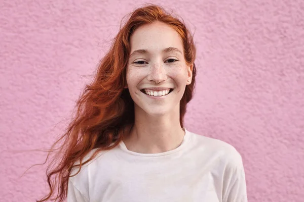 Pembe Şehir Duvarının Üzerinden Neşeyle Gülümseyen Kızıl Saçlı Kadının Portresi — Stok fotoğraf