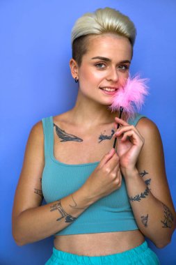 Evcil giysiler giyen, erotik tüylü hatuna dokunan, dövmeli kadının dikey portresi. Seks konsepti için ekipman