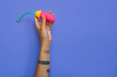 Klitoral uyarılma için mor arka plan üzerinde titreşimli yumurta tutan dövmeli kızın yakın görüntüsü. Yetişkin oyuncakları konsepti. Stok fotoğrafı