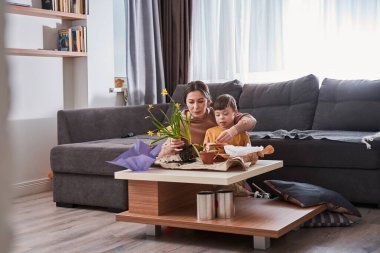 Evinde Down sendromlu oğluyla vakit geçirirken bitkiler için toprak hazırlayan dost canlısı annenin uzun bir görüntüsü.