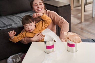 Mutfakta düşük sendromlu, konuşan ve geri dönüşüm için çöp toplayan mutlu beyaz anne ve oğul. Ev kavramında aile zaman geçirme